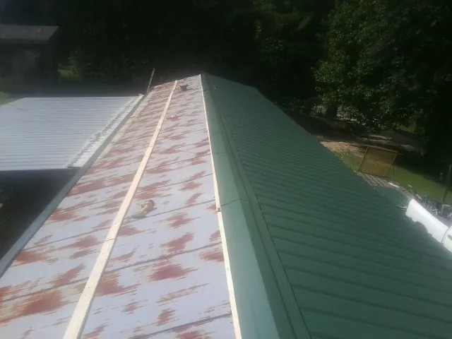Old rusted panels beside newly installed green metal roofing — Wind Damage Roof Repair by Roofing Brothers in Rosedale